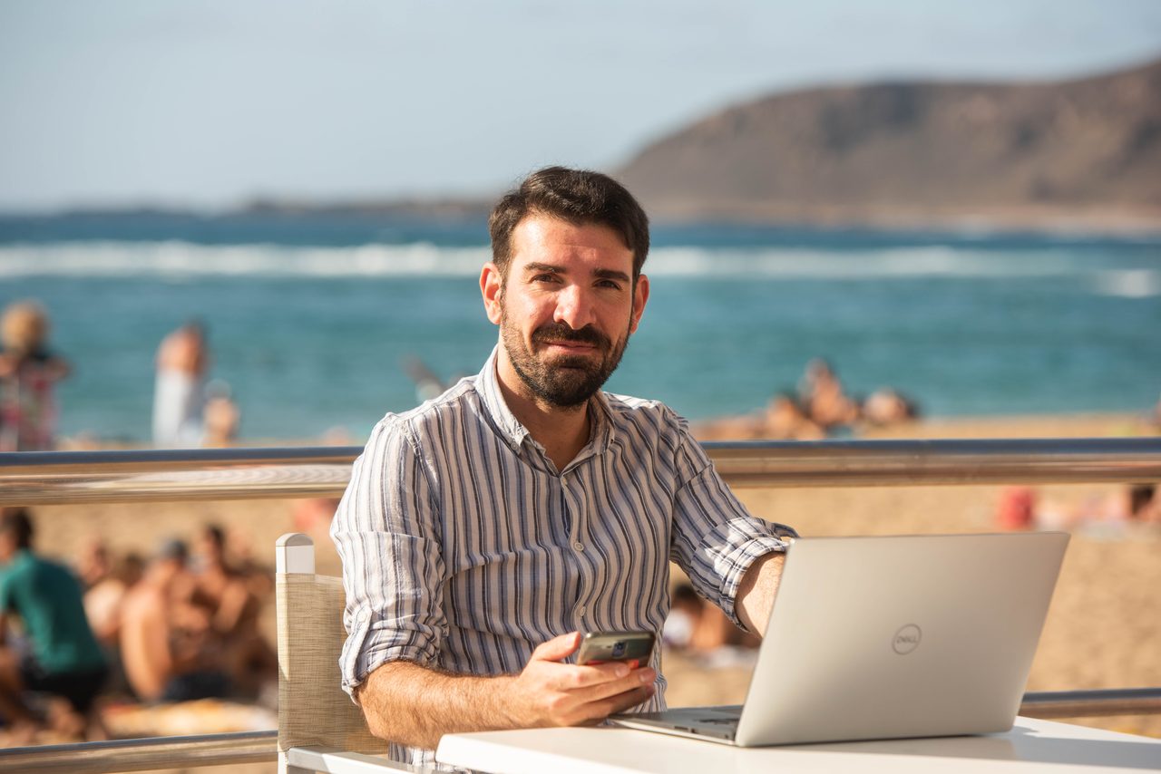 Víctor Gómez trabajando en su negocio digital desde la playa